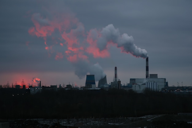 Vista das chaminés fumegantes de uma usina termelétrica nos primeiros raios de sol