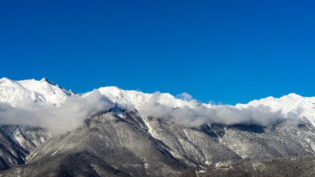 Vista das montanhas do Cáucaso do inverno e nuvens de cima, Krasnaya Polyana, Rússia.