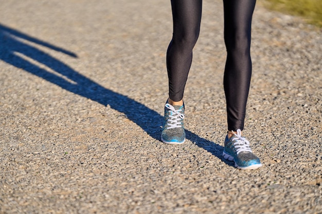 Vista das pernas da atleta feminina em leggings pretas com tênis e espaço para texto