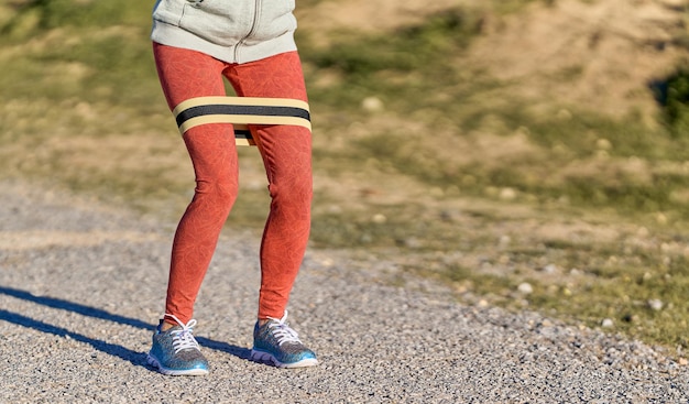 Vista das pernas de mulher exercitando ao ar livre em leggings vermelhas