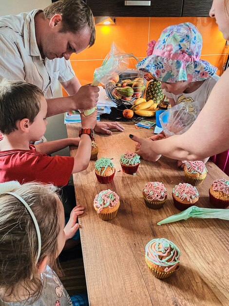 Foto vista de alto ângulo da família com cupcakes na mesa em casa