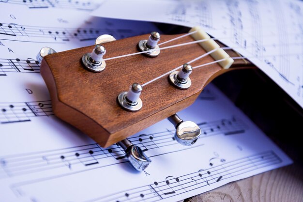 Foto vista de alto ângulo da guitarra sobre notas musicais na mesa