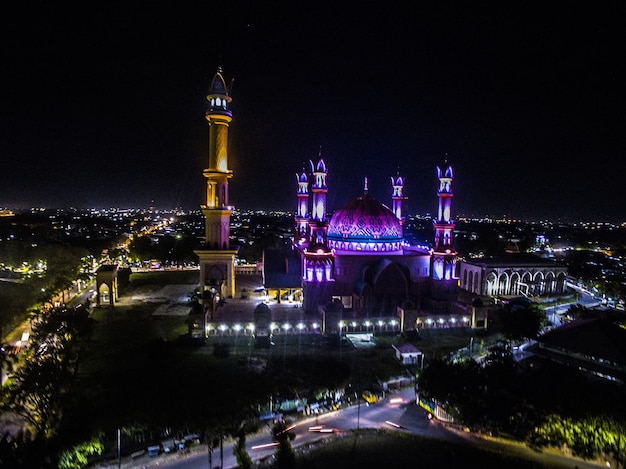 Vista de alto ângulo da mesquita de lombok iluminada em meio à paisagem urbana à noite