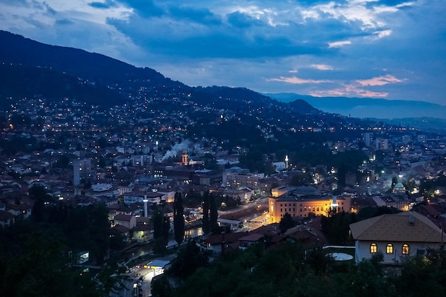 Vista de alto ângulo da paisagem urbana iluminada contra o céu nublado durante o pôr-do-sol