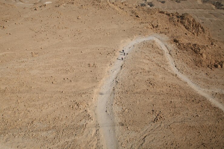 Foto vista de alto ângulo de caminhantes caminhando por uma estrada de terra no deserto de judá