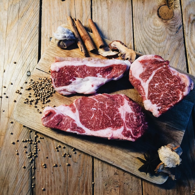 Vista de alto ângulo de carne com especiarias na tábua de cortar