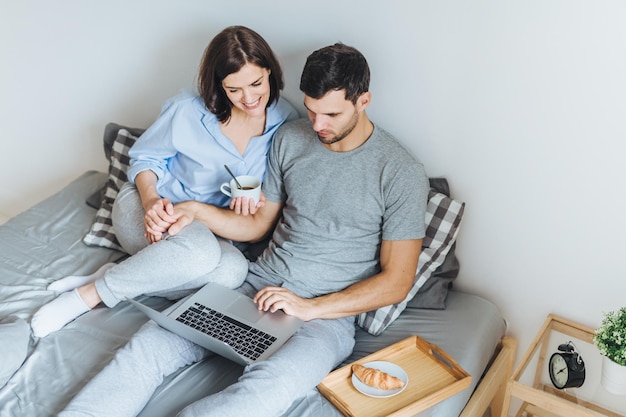 Vista de alto ângulo de casal assistindo vídeo no laptop na cama em casa