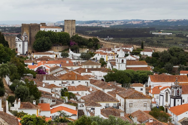 Foto vista de alto ângulo de casas na cidade medieval de obidos com castelo contra o céu