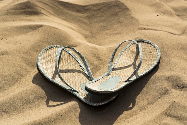 Foto vista de alto ângulo de chinelos na areia na praia