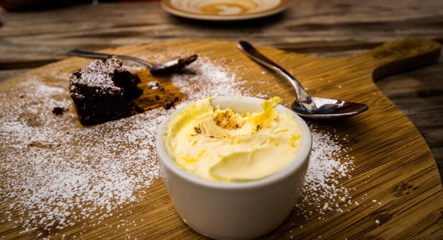 Foto vista de alto ângulo de creme coagulado e brownie com farinha na prancha de corte