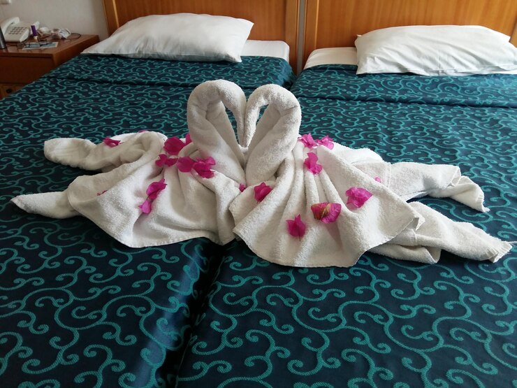 Foto vista de alto ângulo de forma de coração feita com toalhas e flores na cama em casa