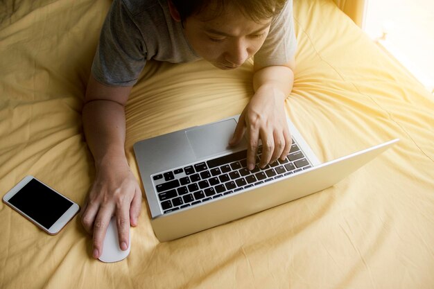 Vista de alto ângulo de homem usando laptop na cama em casa