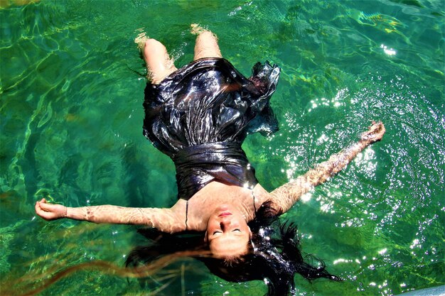 Foto vista de alto ângulo de jovem flutuando na piscina