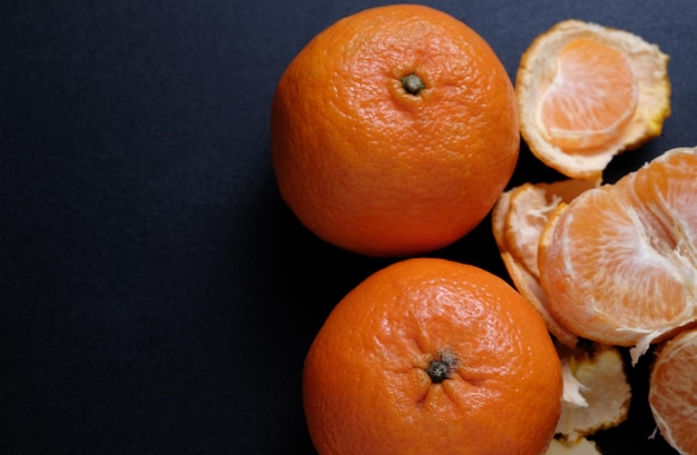 Foto vista de alto ângulo de laranjas com casca sobre fundo preto