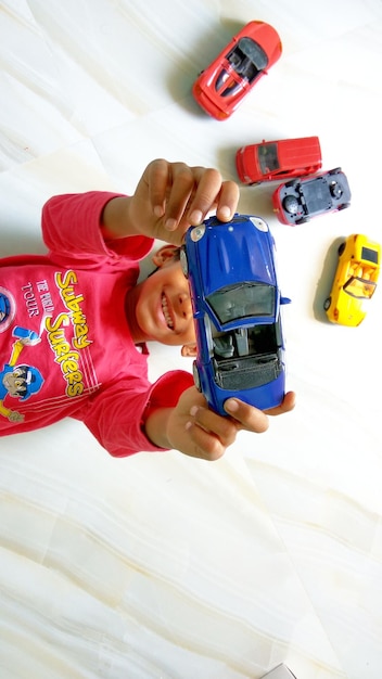 Foto vista de alto ângulo de menino brincando com carros de brinquedo no chão de mármore em casa