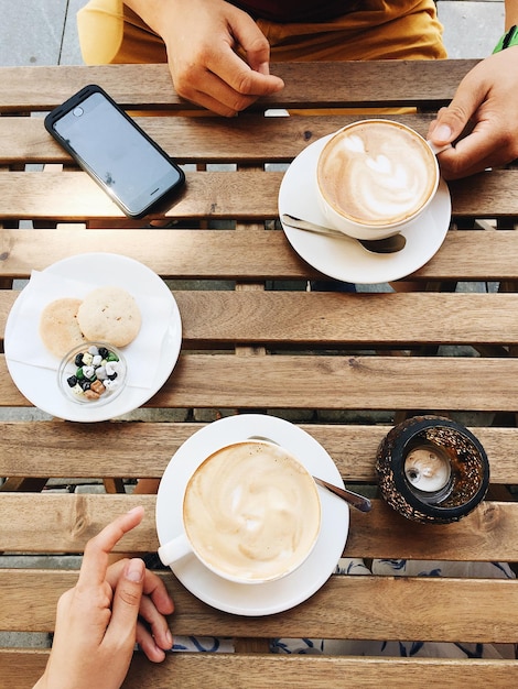 Foto vista de alto ângulo de mulher segurando copos de café em uma mesa de madeira