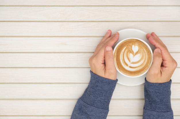 Vista de alto ângulo de mulher segurando xícara de café na mesa