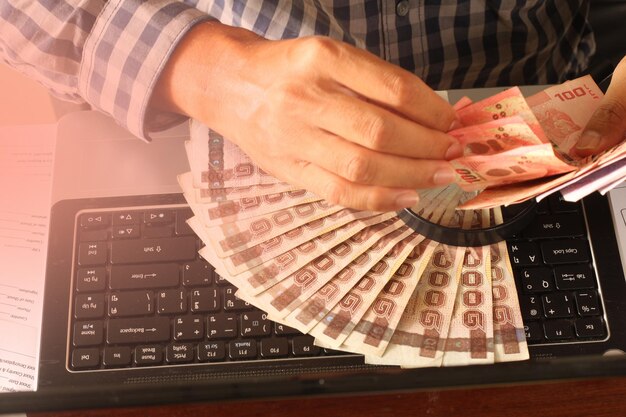 Foto vista de alto ângulo de pessoa contando moeda de papel em um laptop