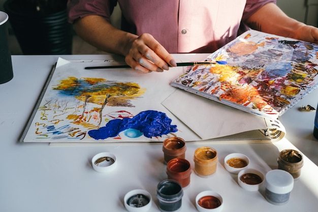 Vista de alto ângulo de pessoa segurando pintura na mesa