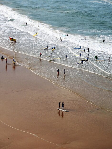 Foto vista de alto ângulo de pessoas com tábuas de surf na praia