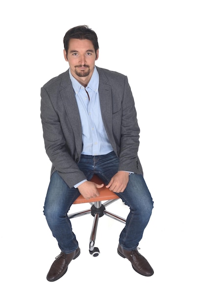 Vista de alto ângulo de um homem com blazer sentado na cadeira, olhando para a câmera em fundo branco