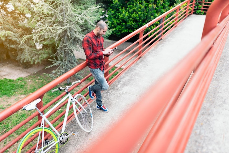 Foto vista de alto ângulo de um homem de pé junto à grade com uma bicicleta