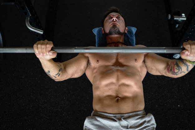 Vista de alto ângulo de um homem forte fazendo exercícios de supino em uma academia