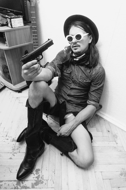 Foto vista de alto ângulo de um homem segurando uma arma enquanto estava sentado no chão em casa