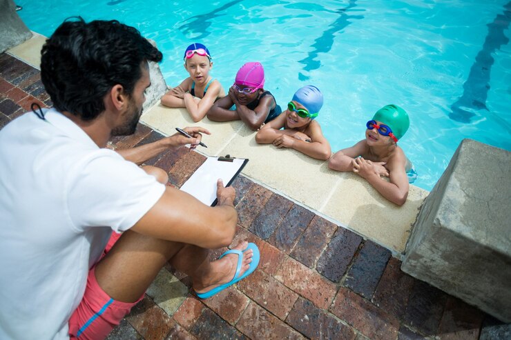 Foto vista de alto ângulo de um instrutor com uma prancheta explicando os pequenos nadadores em pooldise