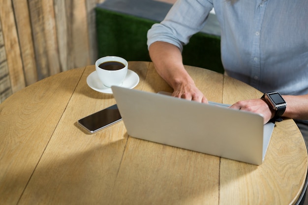 Vista de alto ângulo de um jovem usando o laptop na mesa de um café