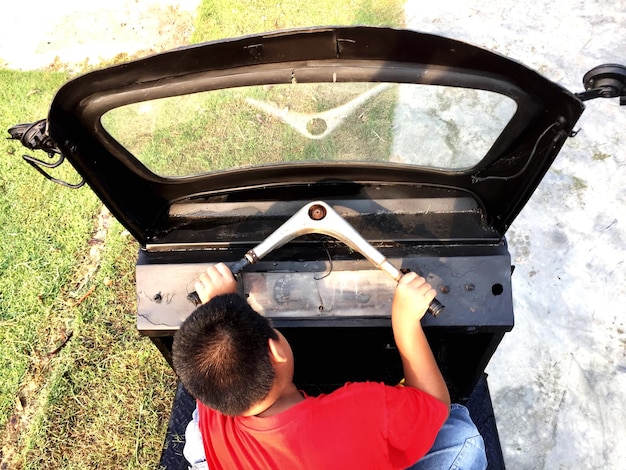 Foto vista de alto ângulo de um menino brincando em um veículo terrestre