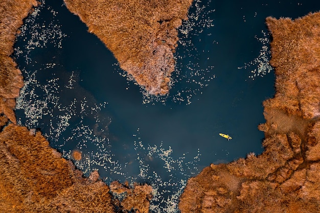 Vista de alto ângulo de um pequeno caiaque turístico no lago negro e prado laranja seco