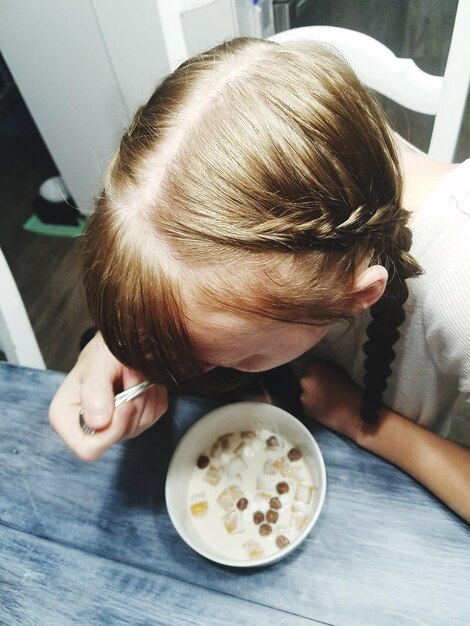Foto vista de alto ângulo de uma adolescente comendo comida em casa