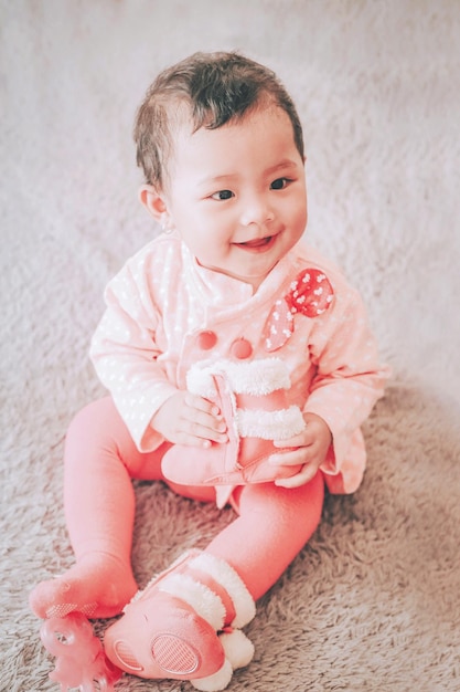 Foto vista de alto ângulo de uma menina bonita e sorridente olhando para longe enquanto está sentada no tapete em casa