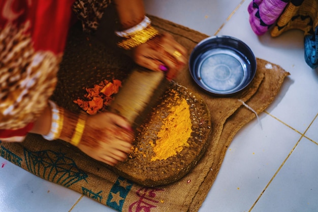 Foto vista de alto ângulo de uma mulher preparando pasta de cúrcuma em um casamento hindu