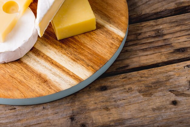 Vista de alto ângulo de vários queijos na tábua de madeira à mesa, copie o espaço