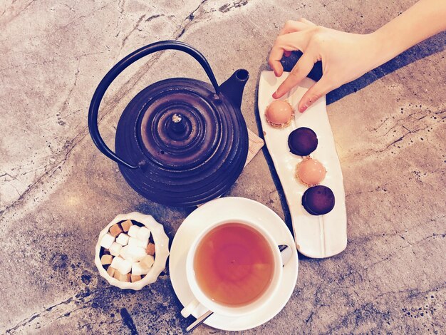 Foto vista de ângulo alto da mão da mulher pegando comida doce do prato na mesa