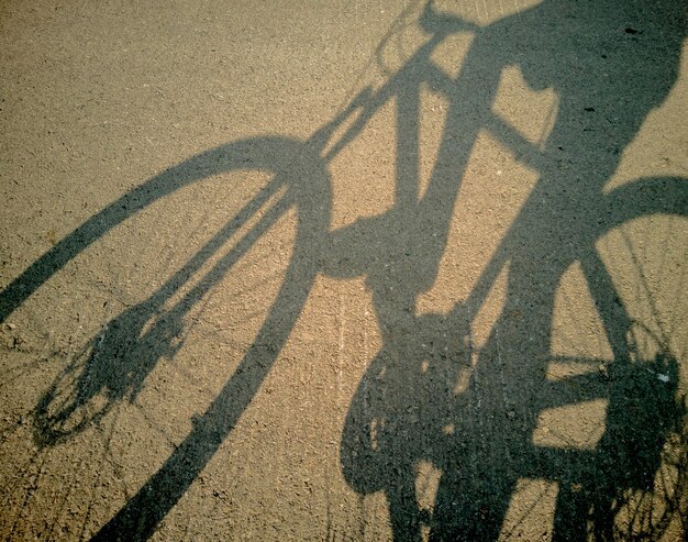 Foto vista de ângulo alto da sombra de uma bicicleta na estrada