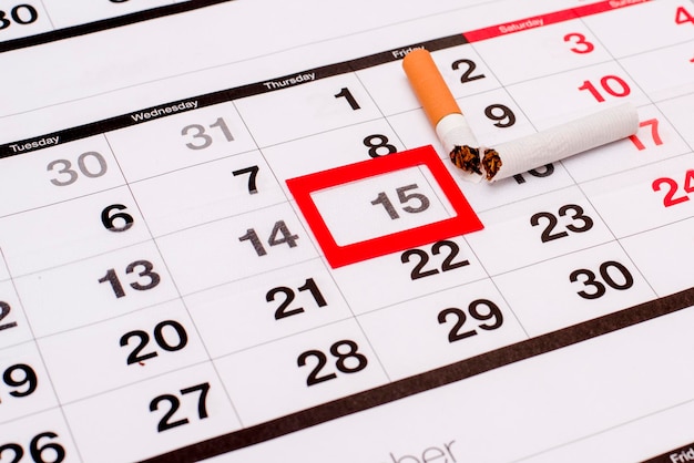 Foto vista de ângulo alto de cigarro quebrado sobre o calendário