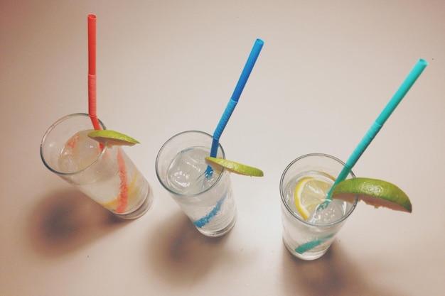 Vista de ângulo alto de coquetéis highball com palhinhas multicoloridas na mesa