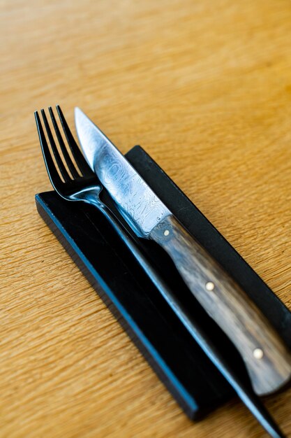 Foto vista de ângulo alto de faca e garfo de aço damascaco na mesa
