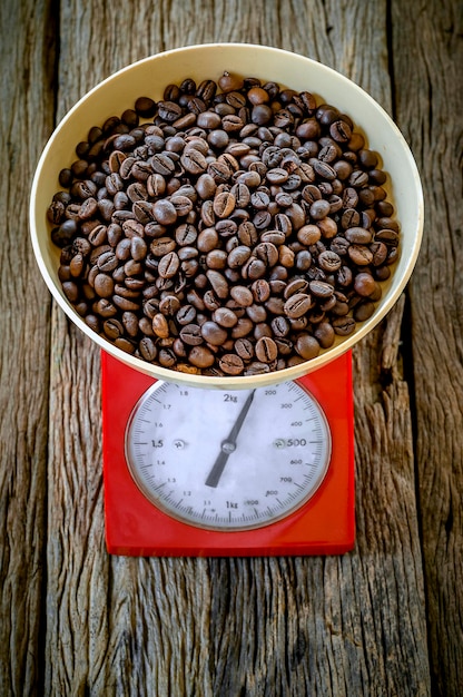 Foto vista de ângulo alto de grãos de café em uma balança vintage vermelha em uma mesa de madeira