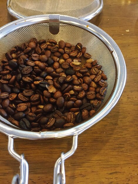 Foto vista de ângulo alto de grãos de café torrados em colander na mesa