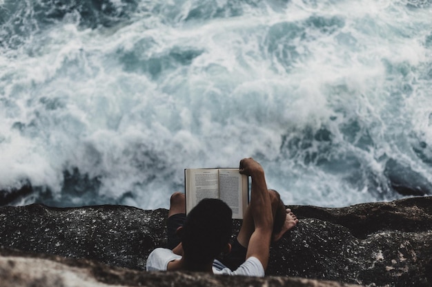 Vista de ângulo alto de homem recortado lendo livro