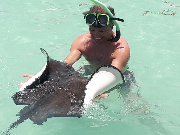 Foto vista de ângulo alto de homem sem camisa nadando com peixes no mar