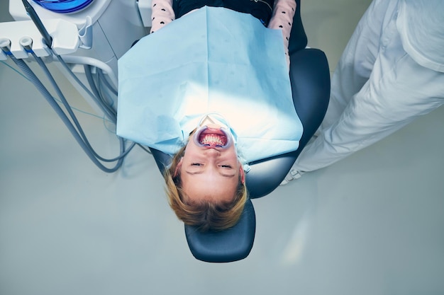 Vista de ângulo alto de menina deitada no consultório do dentista