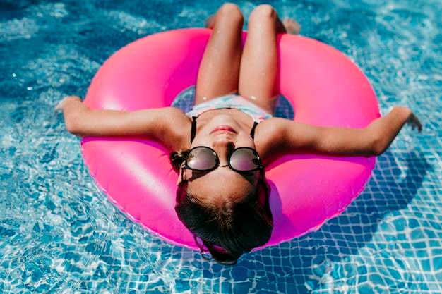 Vista de ângulo alto de menina relaxando em anel inflável na piscina