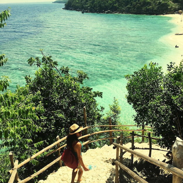 Foto vista de ângulo alto de mulher caminhando em degraus contra o mar na praia