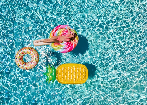 Foto vista de ângulo alto de mulher flutuando em pirulito inflável na piscina