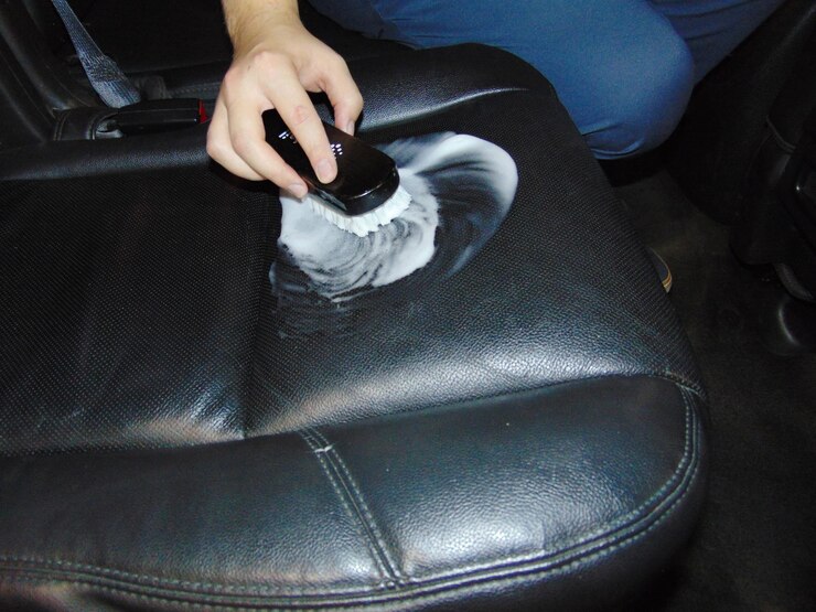 Foto vista de ângulo alto de mulher limpando o assento de couro no carro